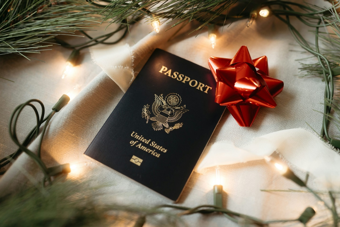 a US passport with a red ribbon and fairy lights